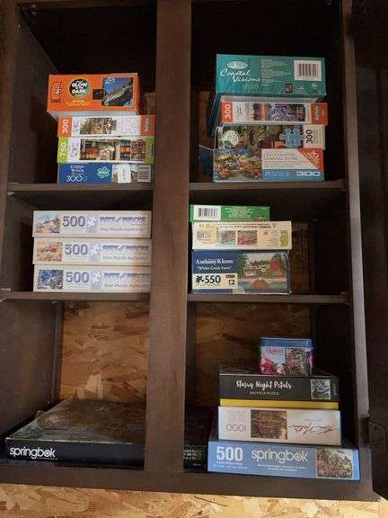 Cupboard full of puzzles including Gone with the Wind on the floor image