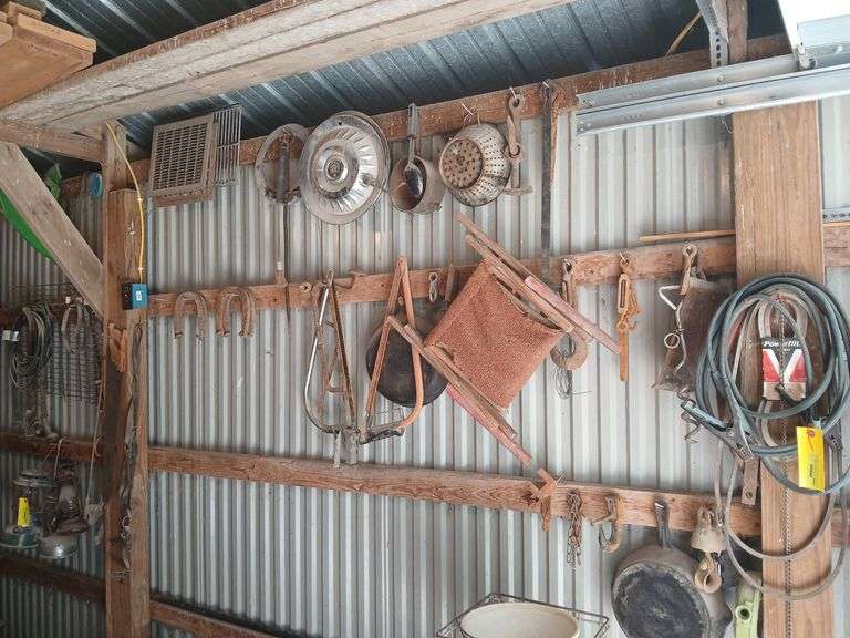Hanging on wall includes cast iron skillet, jumper cables, chain binder, pans, saws, horseshoes, hames etc...