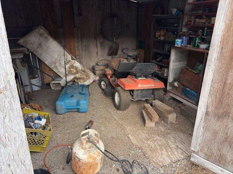 Shed full of treasures, including a Husqvarna riding lawnmower in completely unknown condition, propane weed burner, Rockwell table saw, various nuts, bolts, and hardware image