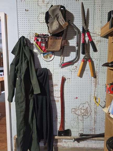 Wall of tools saw, axe, coveralls, tool bags image