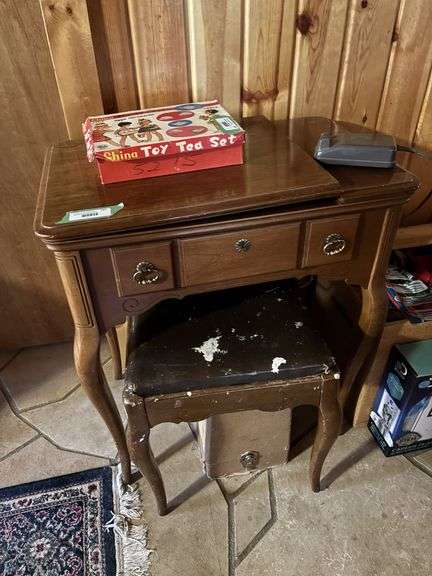 Singer sewing machine in table with bench and lots of additional sewing items in the bench