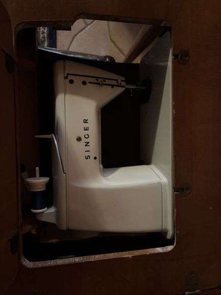 Singer sewing machine in table with bench and lots of additional sewing items in the bench