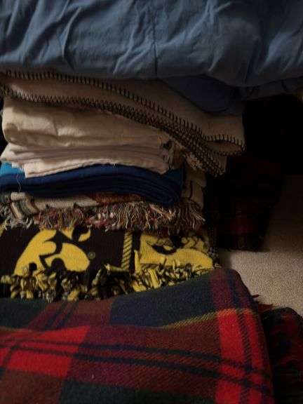 Large pile of bed linens includes electric blanket, sheets and blankets