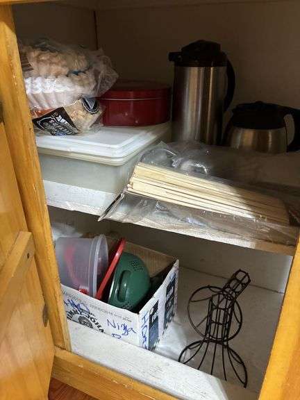 Lower cupboard contents in kitchen - bakeware, pans, colander, plasticware