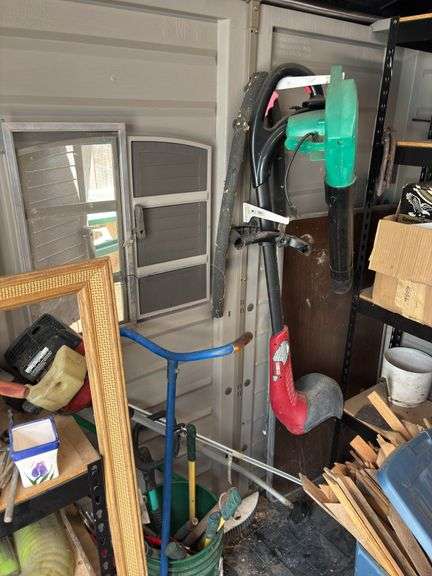 Side wall of garden storage shed includes camp table, electric blower, and string trimmer - shelving unit not included