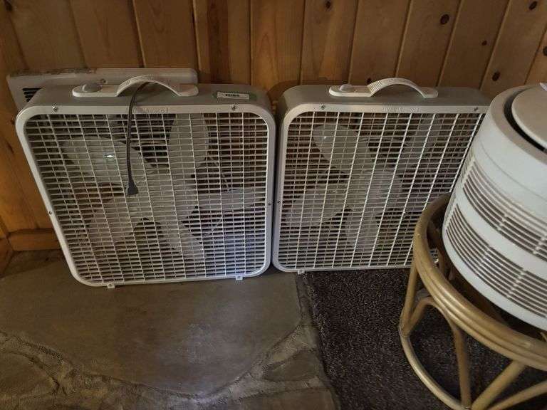 Two box fans and an air purifier on hassock stand