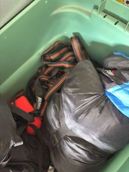 Large tote full of camping supplies, including sleeping bags, camping cookware set, propane burner, bag of rope and more