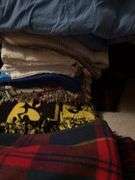 Large pile of bed linens includes electric blanket, sheets and blankets