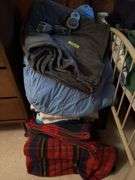 Large pile of bed linens includes electric blanket, sheets and blankets
