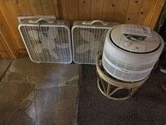 Two box fans and an air purifier on hassock stand