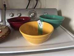 Three colored mixing bowls and apple themed pie carrier