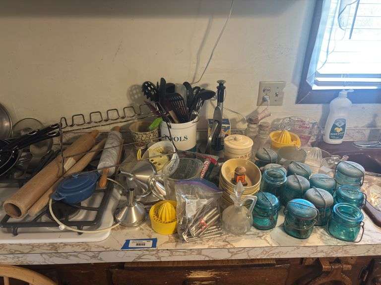 Large assortment of kitchen miscellaneous includes glass measuring cups, dishes, blue lidded glass jars, nutcrackers, kitchen utensils, juicers, rolling pins image