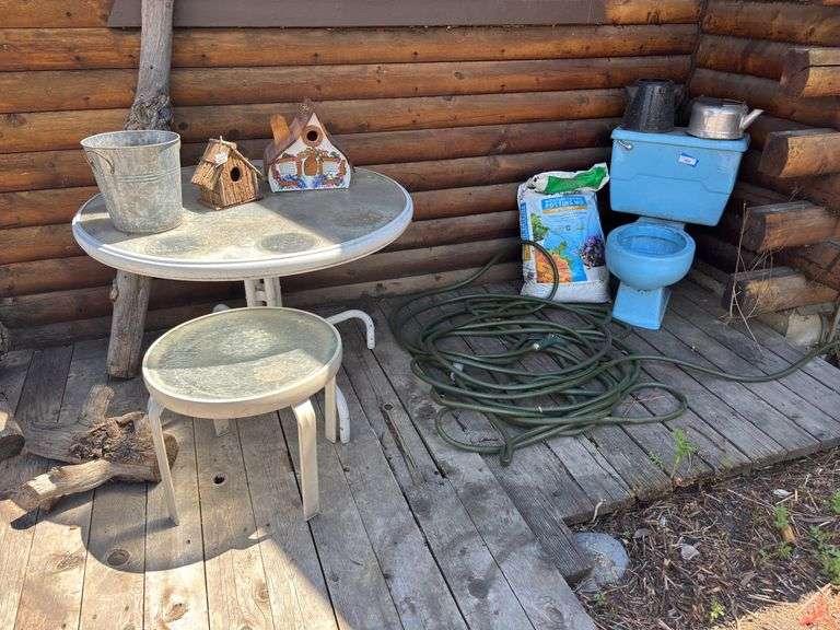 Two glass top patio tables, bird houses, blue yard art toilet, bag of potting mix image