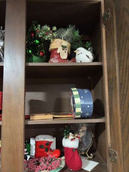 Cupboard full of partially burned candles and holiday decor