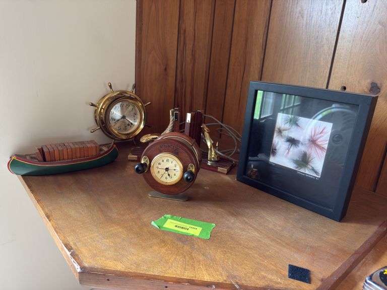 Fishing decor includes Seth Thomas ships wheel clock, S/N fishing lure print, canoe domino set, bookends and Reel Time alarm clock image