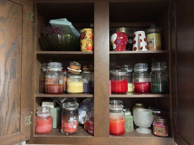 Cupboard full of partially burned candles and holiday decor