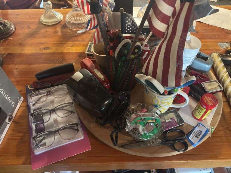 Lazy Susan with lots of office type supplies, electric pencil sharpener, writing utensils, tape, scissors, stapler, reading glasses image