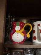 Cupboard full of partially burned candles and holiday decor