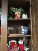 Cupboard full of partially burned candles and holiday decor