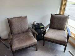 Two padded arm chairs with throw pillows, small side table and decor