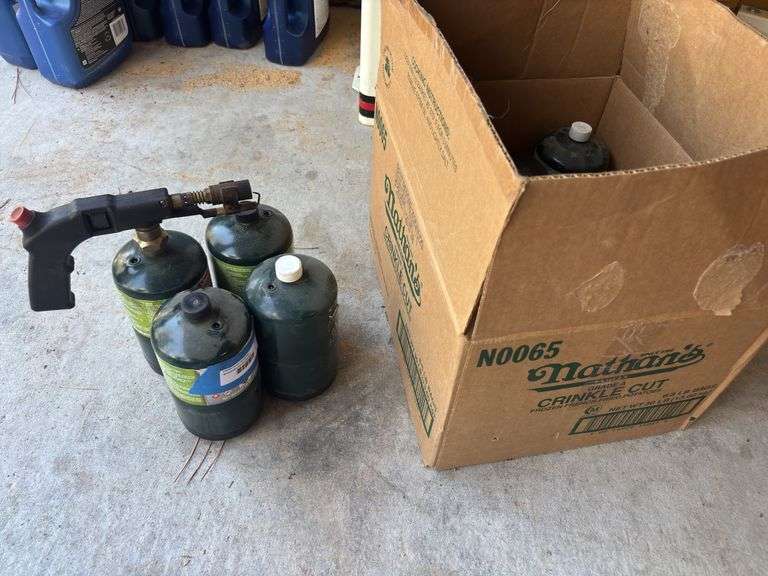 Three full and one partial full small propane tanks with torch and box of empty bottles image