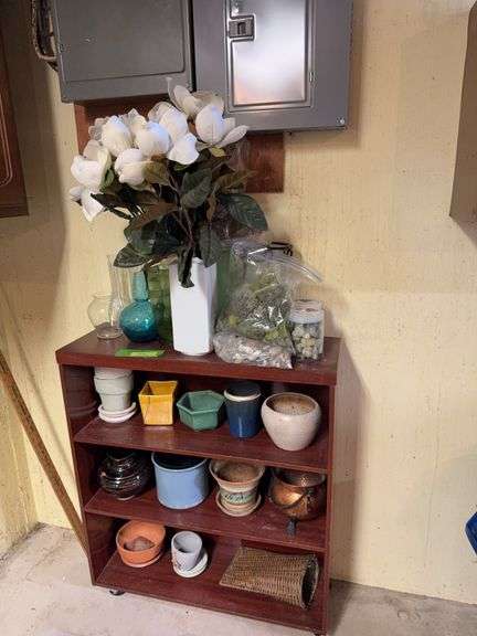 Small bookcase with house plant pots, stones and vases image