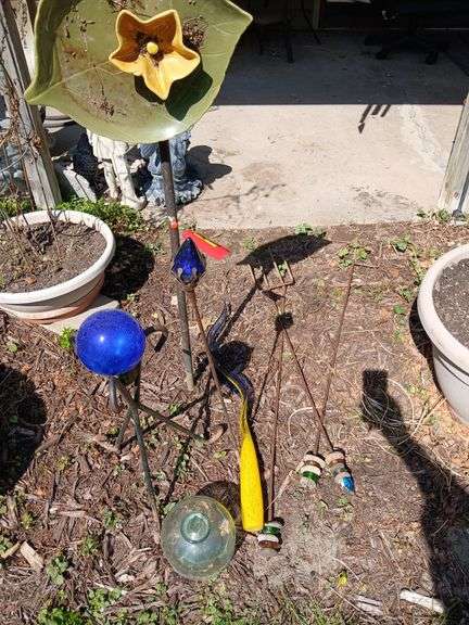 Yard decor includes small gazing ball w stand, plate flower, rocks on stakes, etc image