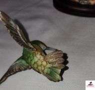 (2) MARURI HUMMINGBIRD FINE  PORCELAIN AND BRONZE STUDIO DESIGN H8905 ANNA'S HUMMINGBIRD WITH LILY, CIRCA 1989, BROKEN LIMB AND A RUBY THROATED HUMMINGBIRD WITH ORCHAD, LEAF MISSING OR BIRD, WING BROKEN - (2) HUMMINGBIRDS - (GREAT ROOM)