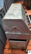 BRINKMANN GAS GRILL - TOP IS 17 1/2" DEEP X 35 1/2" WIDE - SIDE BURNER - APPEARS BEEN PAINTED - ROLLING FEET MISSING / BENT - PROPANE TANK INCLUDED - COVER - (PATIO)
