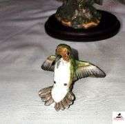 (2) MARURI HUMMINGBIRD FINE  PORCELAIN AND BRONZE STUDIO DESIGN H8905 ANNA'S HUMMINGBIRD WITH LILY, CIRCA 1989, BROKEN LIMB AND A RUBY THROATED HUMMINGBIRD WITH ORCHAD, LEAF MISSING OR BIRD, WING BROKEN - (2) HUMMINGBIRDS - (GREAT ROOM)