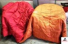 (2) SLEEPING BAGS - RED AND ORANGE - BAG OF TOWELS AND WASH CLOTHES - DEPENDS AND LADIES PADS - (GARAGE)