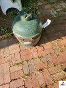 BIG GREEN EGG BARBEQUE GRILL - SMALL SIZE - GREEN COLOR - TOP COVER CRACKED HAS CHIP MISSING - (BESIDE GARAGE)