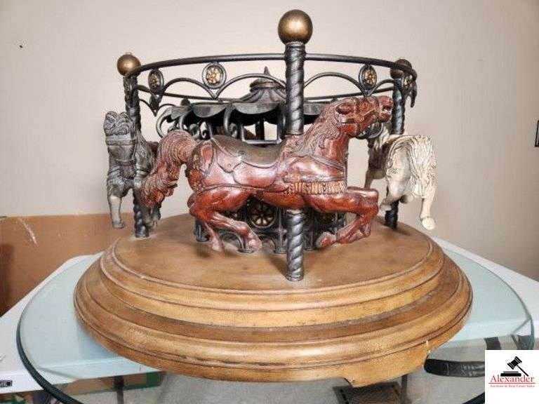 ATTRACTIVE CAROUSEL REVOLVING COCKTAIL TABLE WITH GLASS TABLE - BEVELED EDGE GLASS BASE, 44" DIAMETER - STURDY METAL BASE WITH WOOD TONE - ANTIQUE CRACKLE FINISH - 4 BEAUTIFUL COMPOSITE CAROUSEL HORSES - HORSES SPIN ON BASE - BASE 34" WIDE - TOTAL HEIGHT WITH GLASS 21 1/2" TALL - (MASTER BEDROOM) image