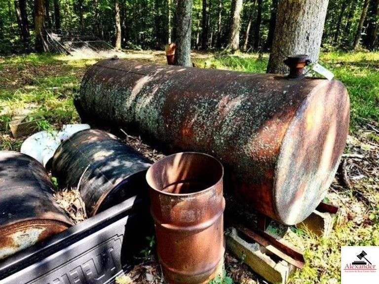 HORIZONTAL GAS TANK ON SLIDES CONDITION UNKNOWN - (3) 55 GALLON DRUMS - SMALL OIL DRUM - USED TRUCK BED LINER - ORANGE DRUM APPEARS FILLED WITH OIL - DO NOT DUMP OUT - & PALLET OF 5 GAL.BUCKET - 2 1/2 GAL. JUGS - MISC. - BURN OIL - WHITE PLASTIC BARREL(WOODS) image
