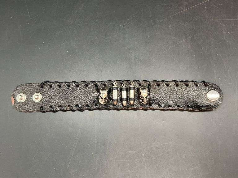 Black leather-like snap bracelet enhanced with skulls and ammo-like accents in center….band shows slight wear from normal use image