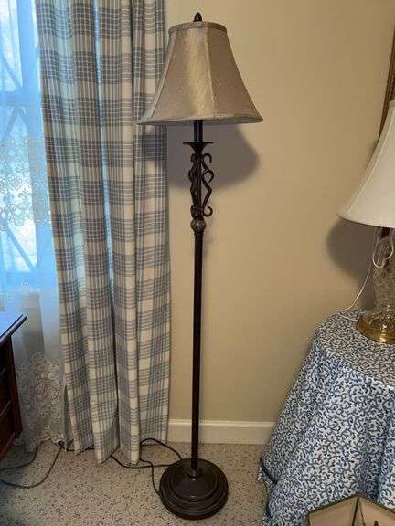 Traditional floor lamp featuring a dark bronze-like finish, metal scroll base with marble-like cylindrical accent and a beige flare shade….61” tall image