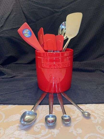 Red stone are utensil crock with kitchen utensils and set of silver metal measuring spoong image