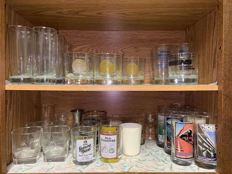 Contents of bottom 2 shelves of glassware….novelty whiskey glasses, train related novelty highball glasses, City of Memphis whiskey glasses and more image