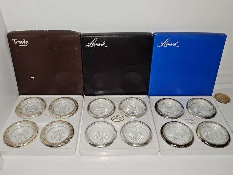 Three boxes of silver plate rimmed coasters or ashtrays. One box has not been opened.