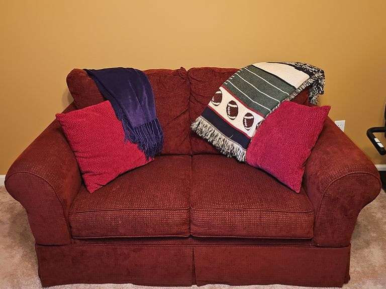 Ashley Furniture burgundy loveseat. 62X36x36 in tall. Seat height 18 in. Includes pillows and throws as shown in last photo.