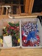 Two tubs. One containing artificial flowers, one containing 4th of July decorative items.