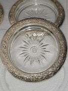Three boxes of silver plate rimmed coasters or ashtrays. One box has not been opened.