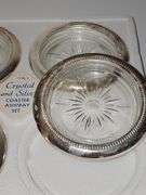 Three boxes of silver plate rimmed coasters or ashtrays. One box has not been opened.