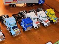Grouping of diecast tractor-trailer toys and others from various makers.