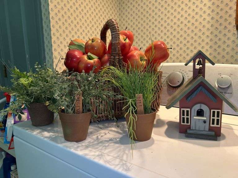 Basket of artificial apples, pots of artificial herbs and musical wooden schoolhouse birdhouse that plays “School Days” image