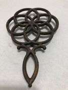Vintage Wilton cast iron trivet. Concentric circle design forming a flower. 9 x 6”. Footed.
