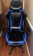 Blue and black rolling high back racing gaming chair, adjustable with foot rest.