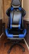 Blue and black rolling high back racing gaming chair, adjustable with foot rest.