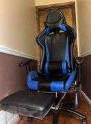 Blue and black rolling high back racing gaming chair, adjustable with foot rest.