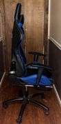 Blue and black rolling high back racing gaming chair, adjustable with foot rest.